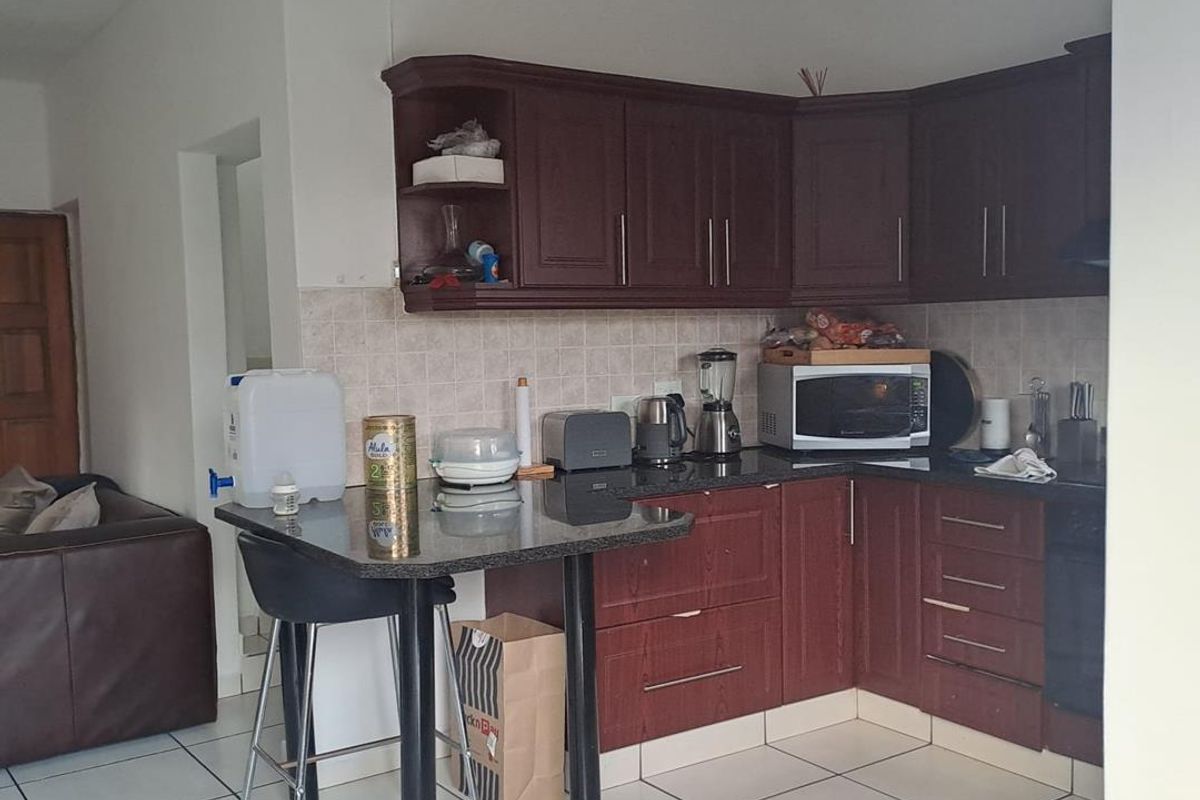 A functional kitchen featuring dark wood cabinetry, granite countertops, a breakfast bar, and tiled flooring, offering a practical layout for daily use.
