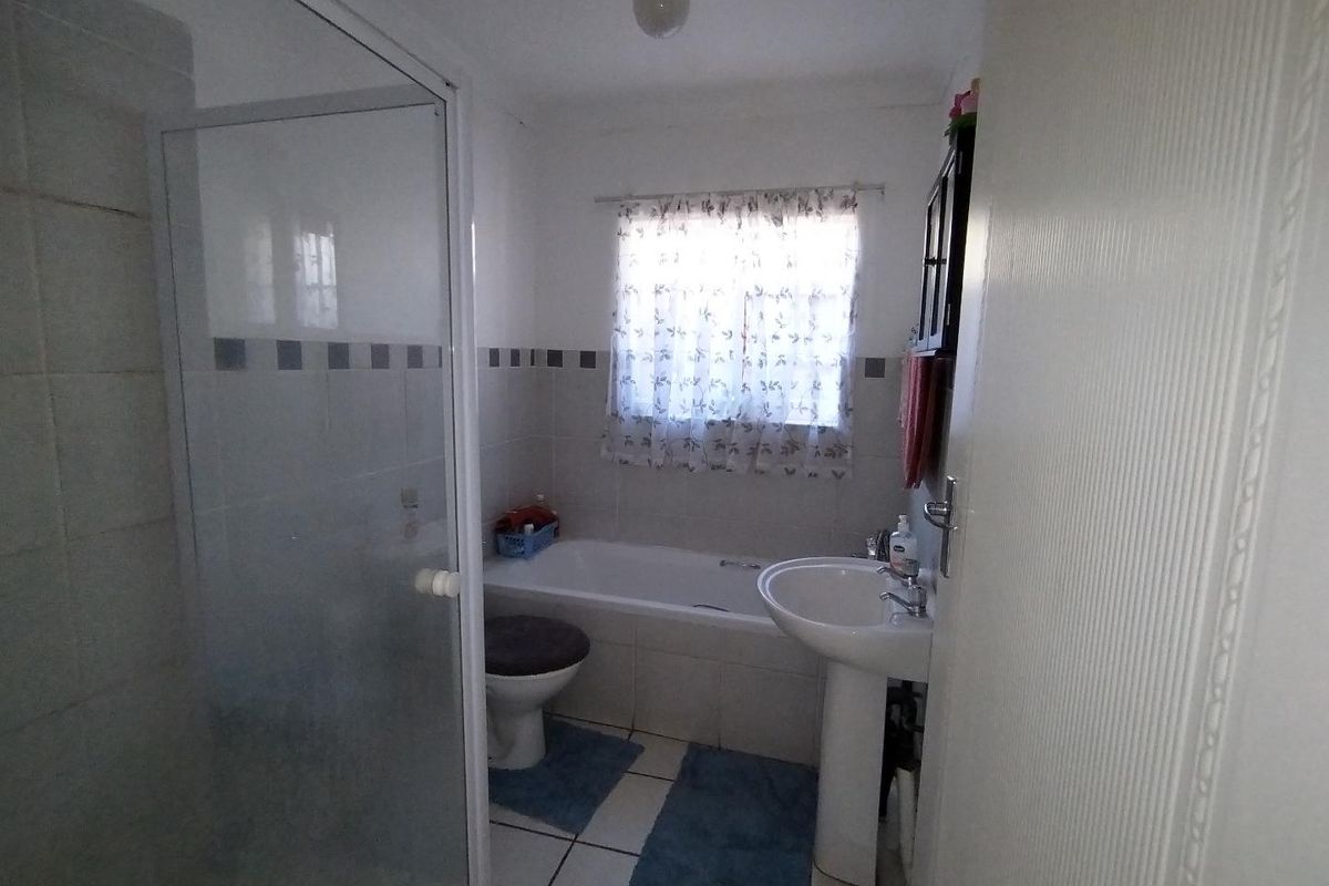 A functional bathroom featuring a shower enclosure, bathtub, pedestal basin, and toilet with tiled finishes.