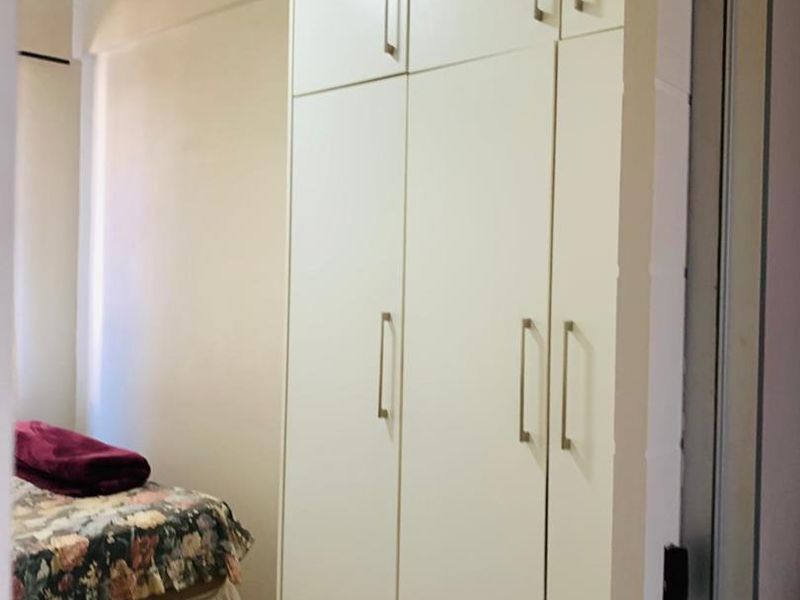 A bedroom featuring a tall, white built-in wardrobe with modern handles, providing ample storage space.