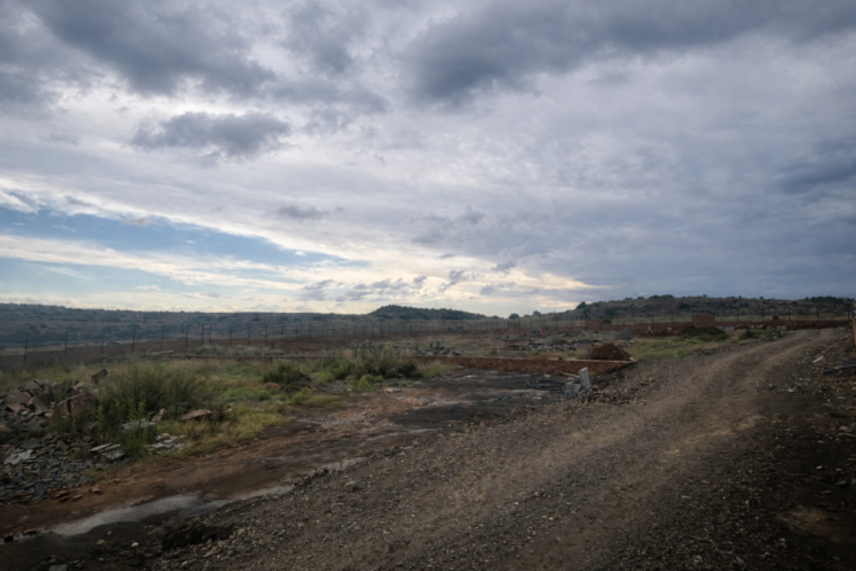 An undeveloped plot of land featuring a dirt access road, perimeter fencing, and natural landscape, suitable for future retirement village development.