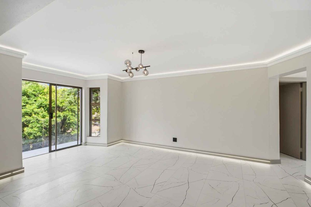 Bright and spacious living area featuring modern marble-look floor tiles, recessed ceiling lighting, and large sliding glass doors leading to an outdoor space.