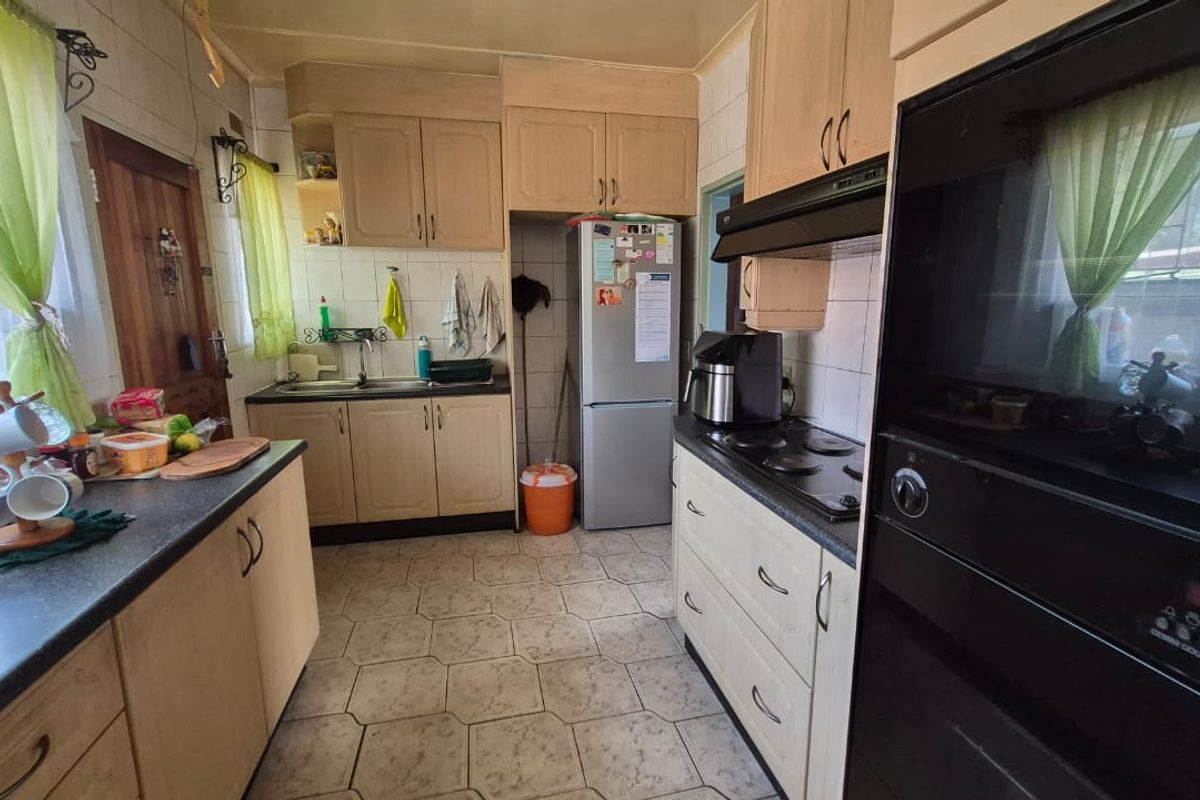 A functional kitchen featuring laminate cabinetry, built-in oven, electric hob, extractor fan, and tiled flooring with a practical layout.