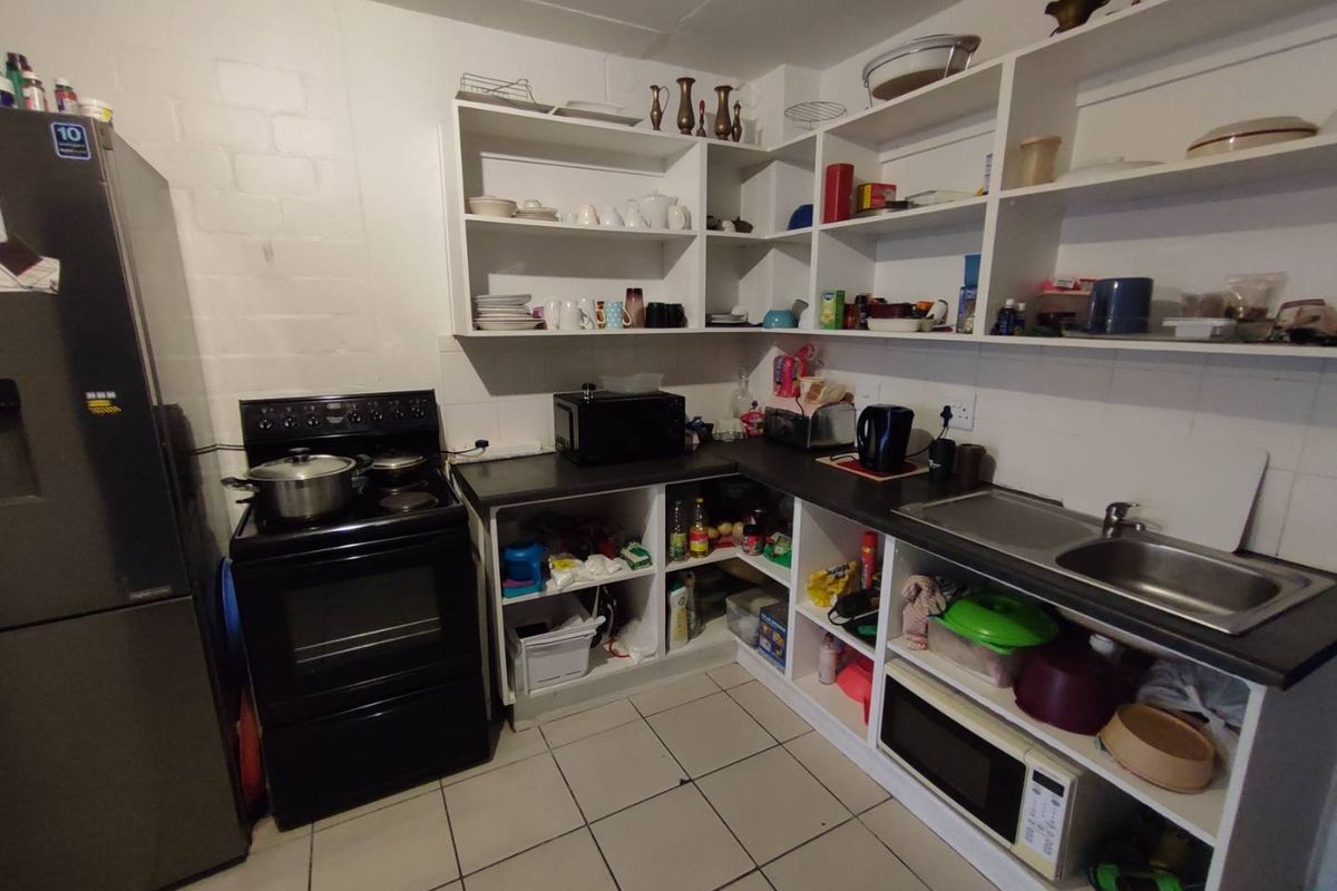 A functional kitchen featuring open shelving, a built-in sink, and a freestanding stove, offering a practical layout for daily meal preparation.