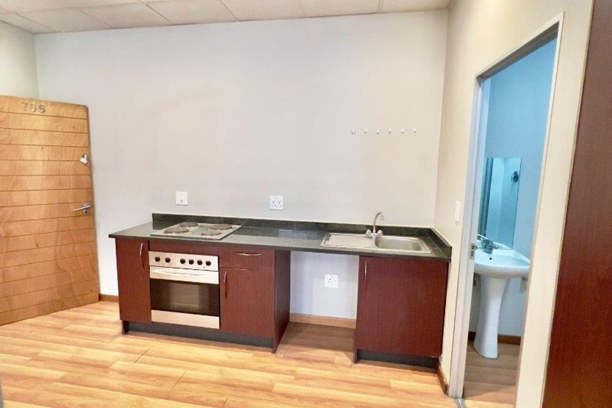 Compact kitchenette featuring built-in oven, hob, and sink, with adjacent bathroom access. The space is vacant and ready for renovation.