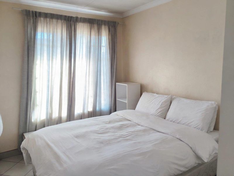 A simple bedroom featuring tiled flooring and a window with curtain fittings, providing a neutral space ready for personalization.