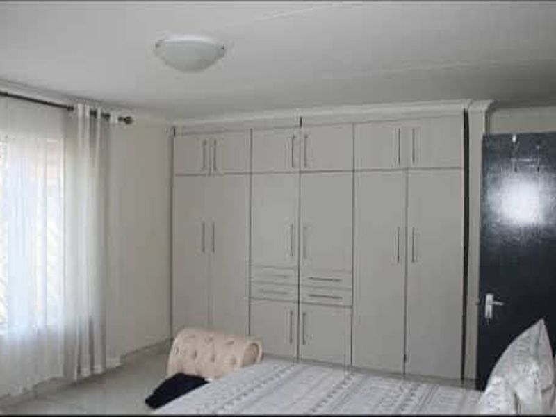 A well-maintained bedroom featuring extensive floor-to-ceiling built-in cupboards providing ample storage space and neutral finishes.