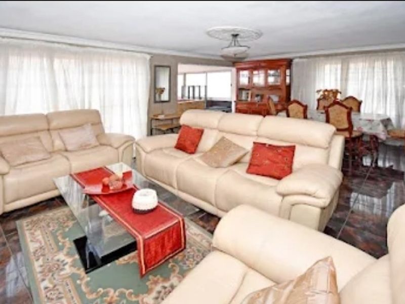 Spacious open-plan living and dining area featuring tiled flooring and decorative ceiling roses, offering a versatile layout for comfortable family living.