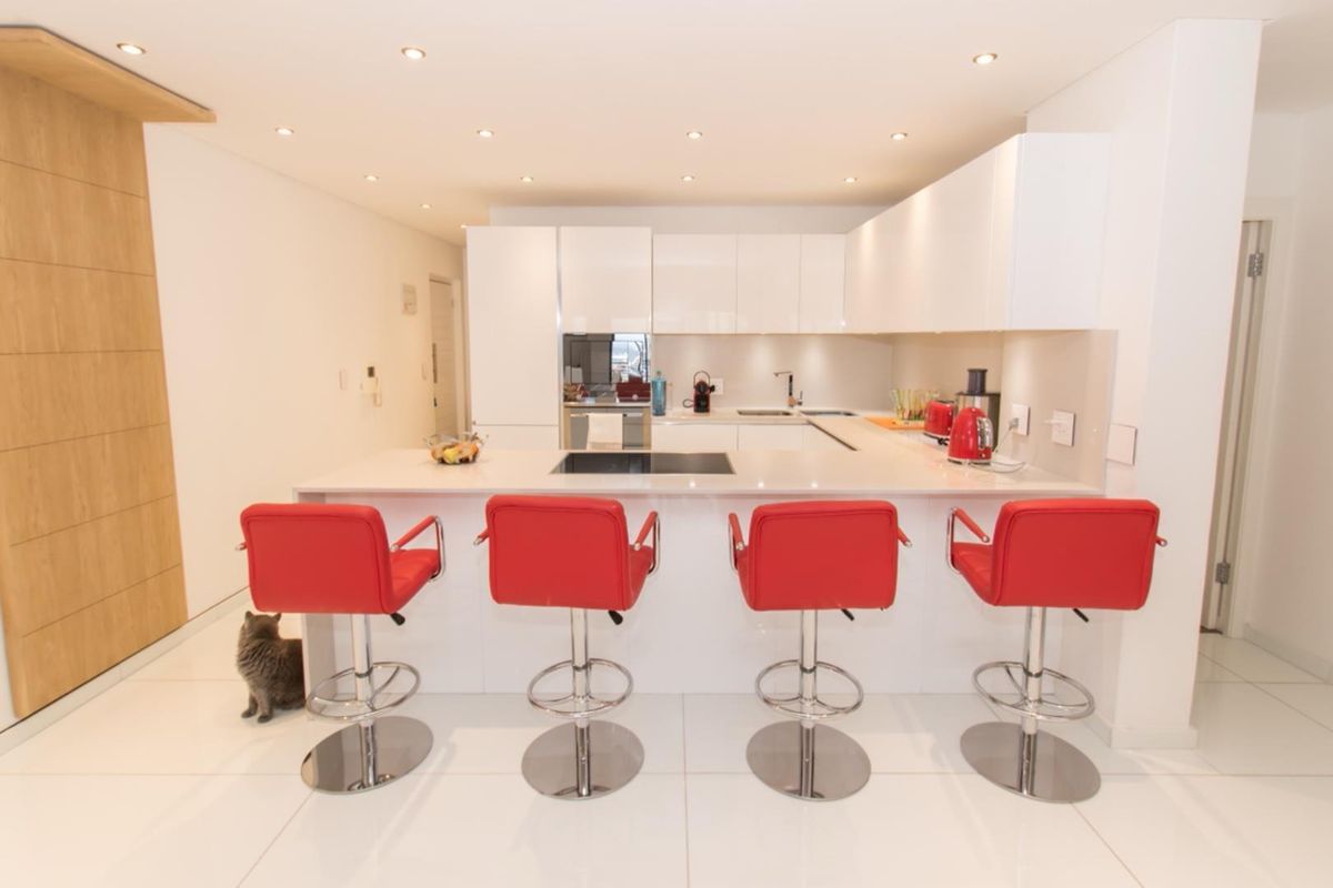Modern kitchen featuring sleek white cabinetry, stone countertops, integrated hob, and recessed lighting, creating a clean and functional culinary space.