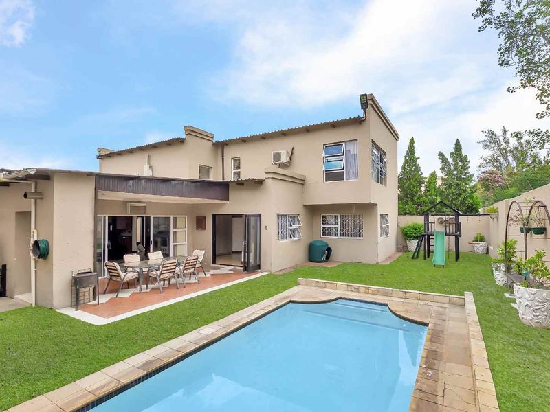 Rear view of the house featuring a swimming pool, covered patio area, and a private garden with boundary walls.