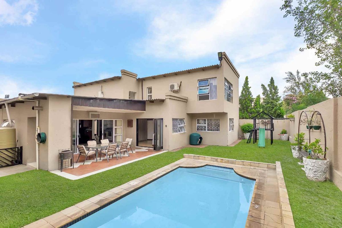 Rear view of the house featuring a swimming pool, covered patio area, and a private garden with boundary walls.