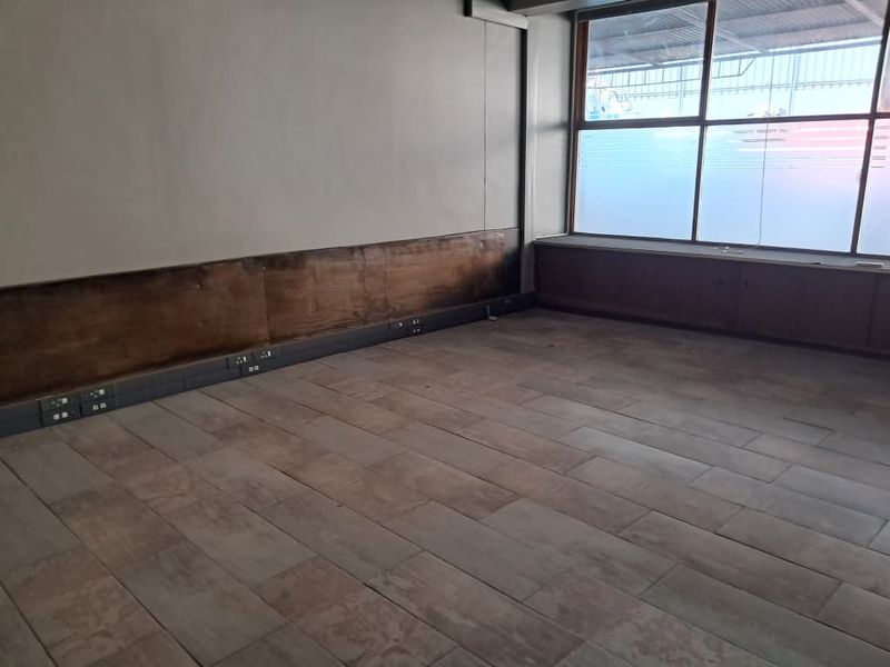 An empty office space featuring large windows, tiled flooring, and perimeter electrical trunking, suitable for a professional workspace setup.