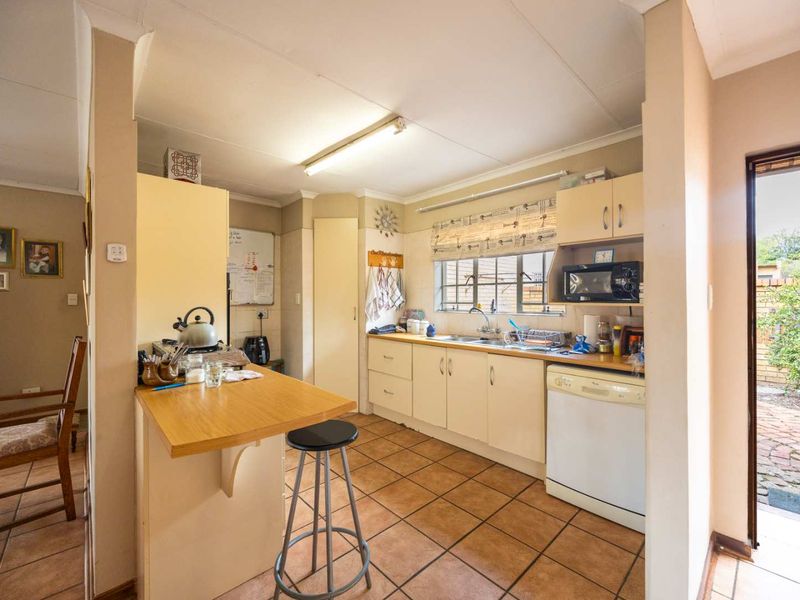 A functional kitchen featuring built-in cabinetry, laminate countertops, and tiled flooring, with direct access to the exterior through a side door.