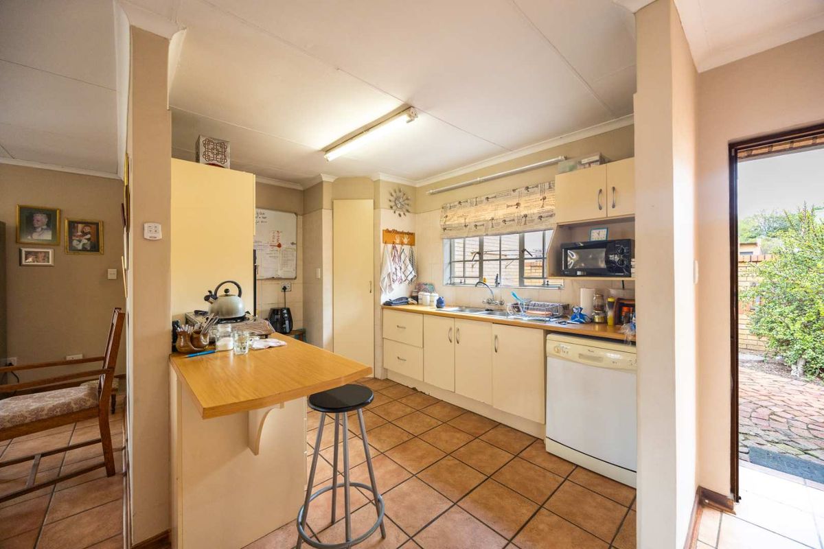 A functional kitchen featuring built-in cabinetry, laminate countertops, and tiled flooring, with direct access to the exterior through a side door.