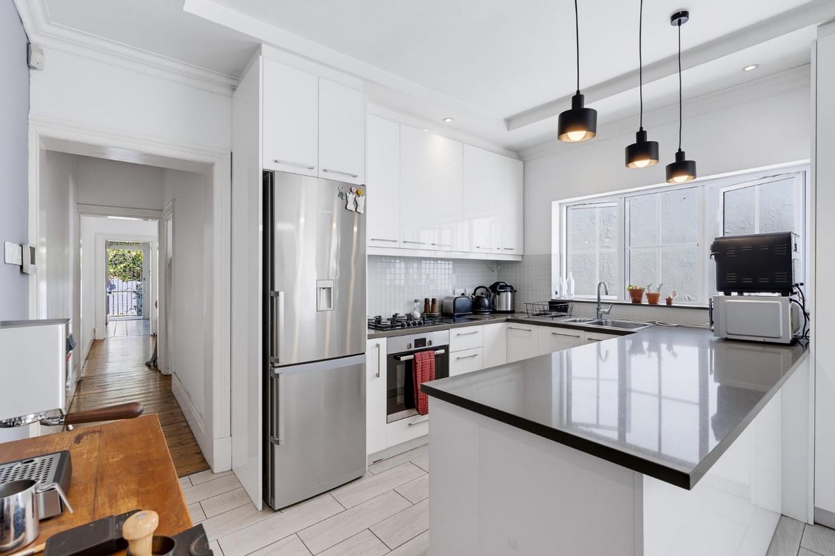 Modern kitchen featuring white cabinetry, stone countertops, integrated gas cooktop, built-in oven, and stylish pendant lighting, offering a clean and functional workspace.