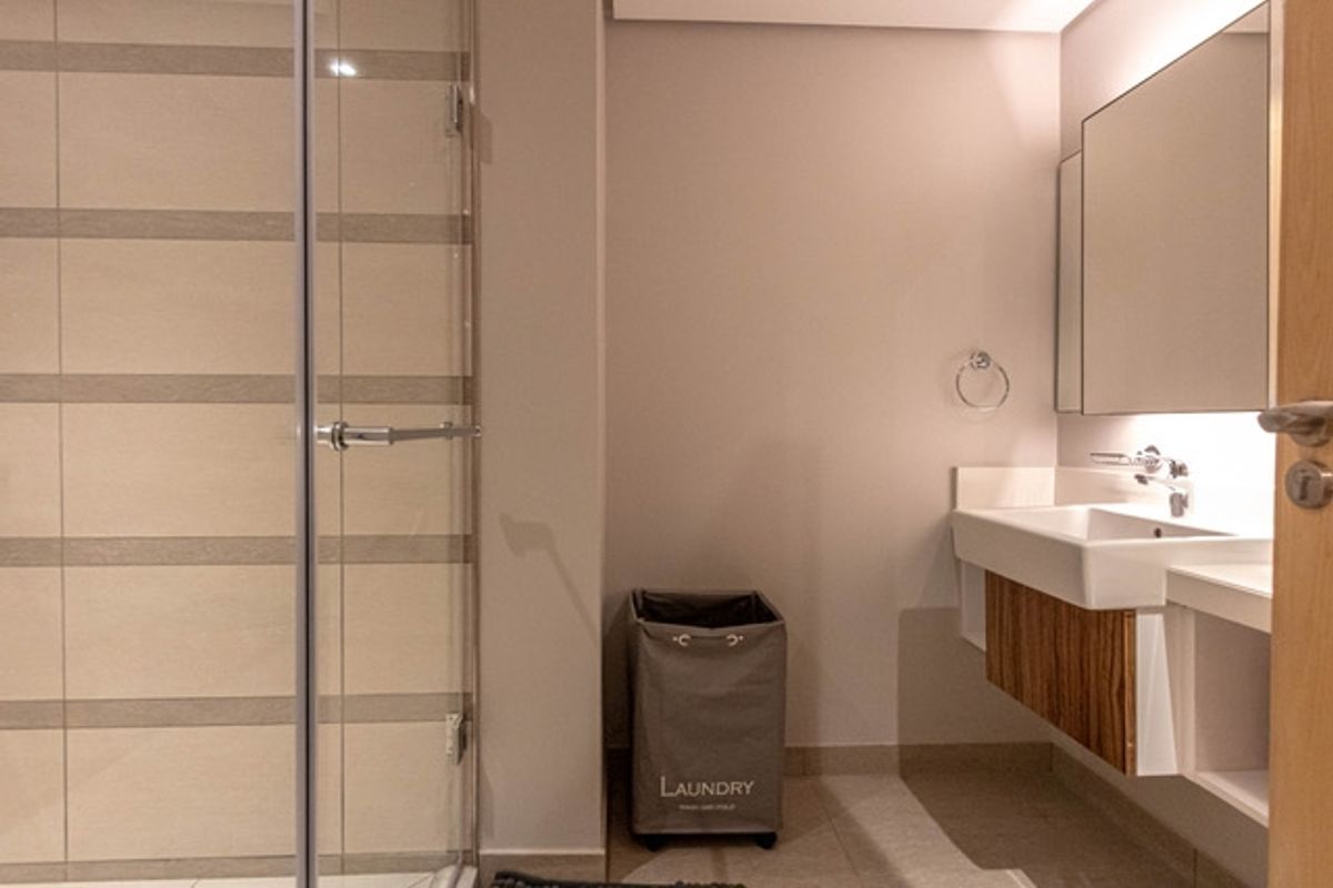 Modern bathroom featuring a glass-enclosed shower, wall-mounted vanity with integrated basin, and a large mirror.