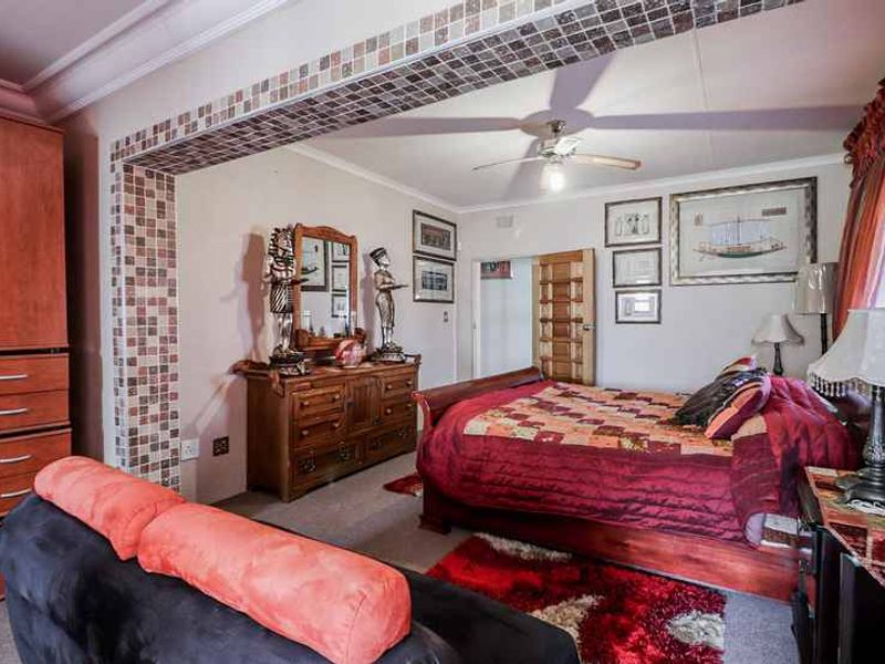 Spacious bedroom featuring a decorative mosaic tile archway, ceiling fan, and built-in cabinetry, offering a comfortable and functional living space.