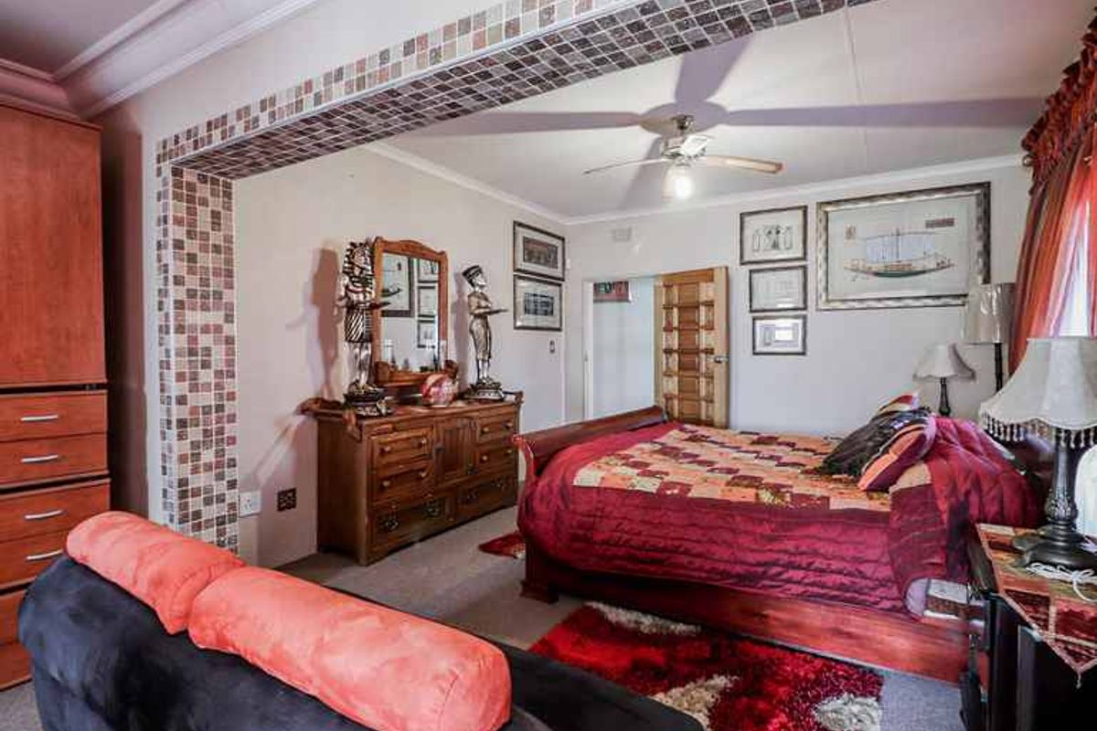 Spacious bedroom featuring a decorative mosaic tile archway, ceiling fan, and built-in cabinetry, offering a comfortable and functional living space.