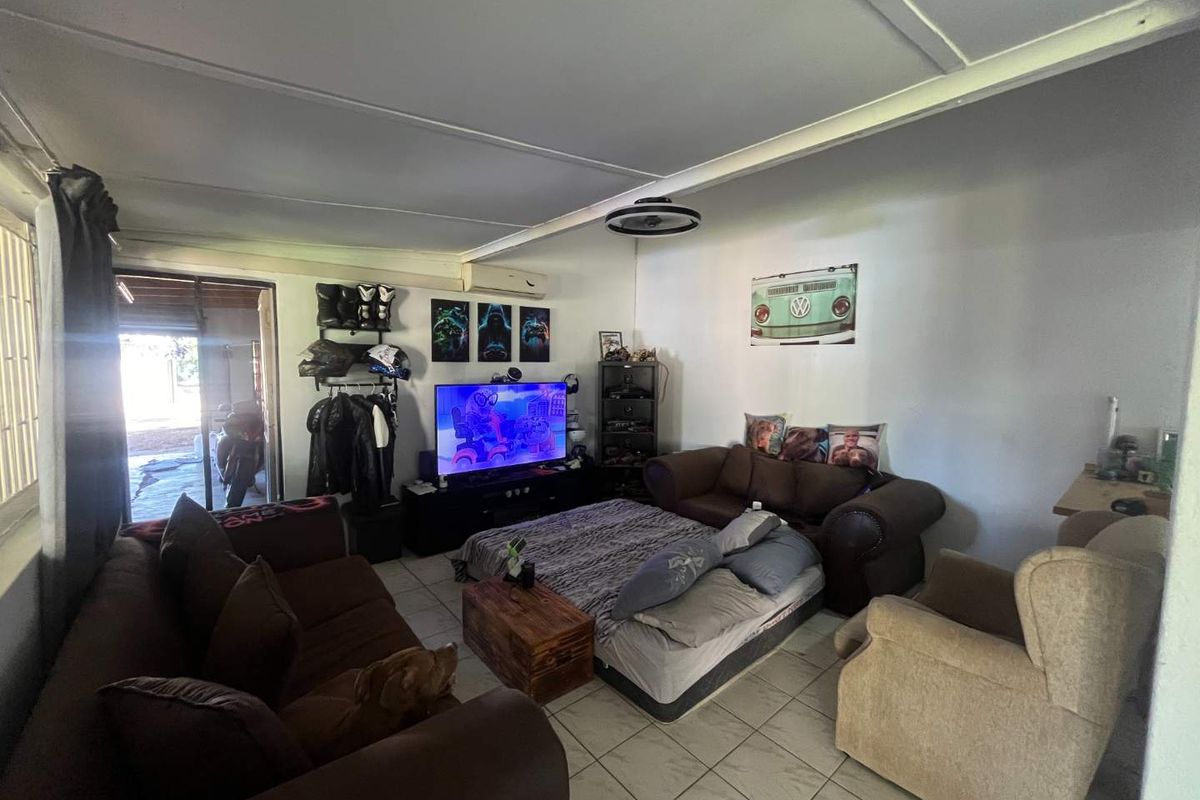 A living room area featuring tiled flooring, a ceiling-mounted light fixture, and direct access to an outdoor patio space.