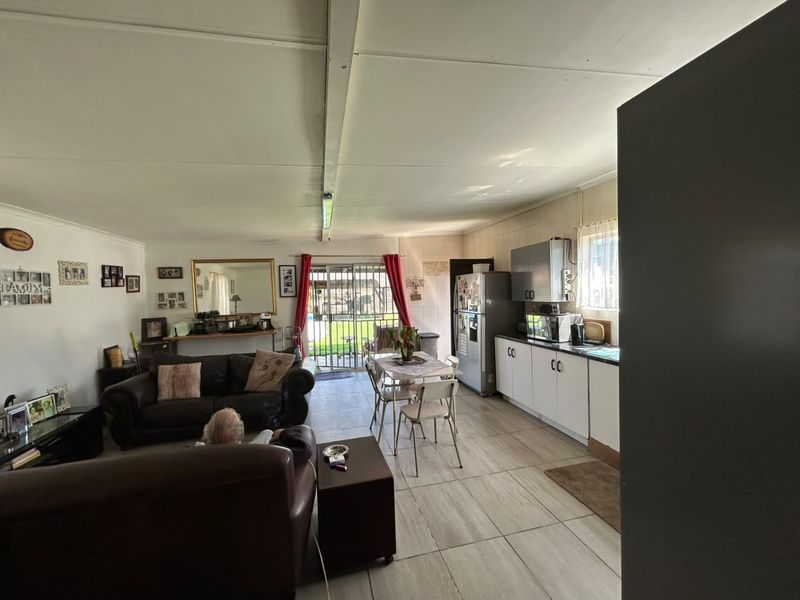 Open plan living and kitchen area featuring tiled flooring, functional cabinetry, and direct access to the rear garden through a sliding glass door.