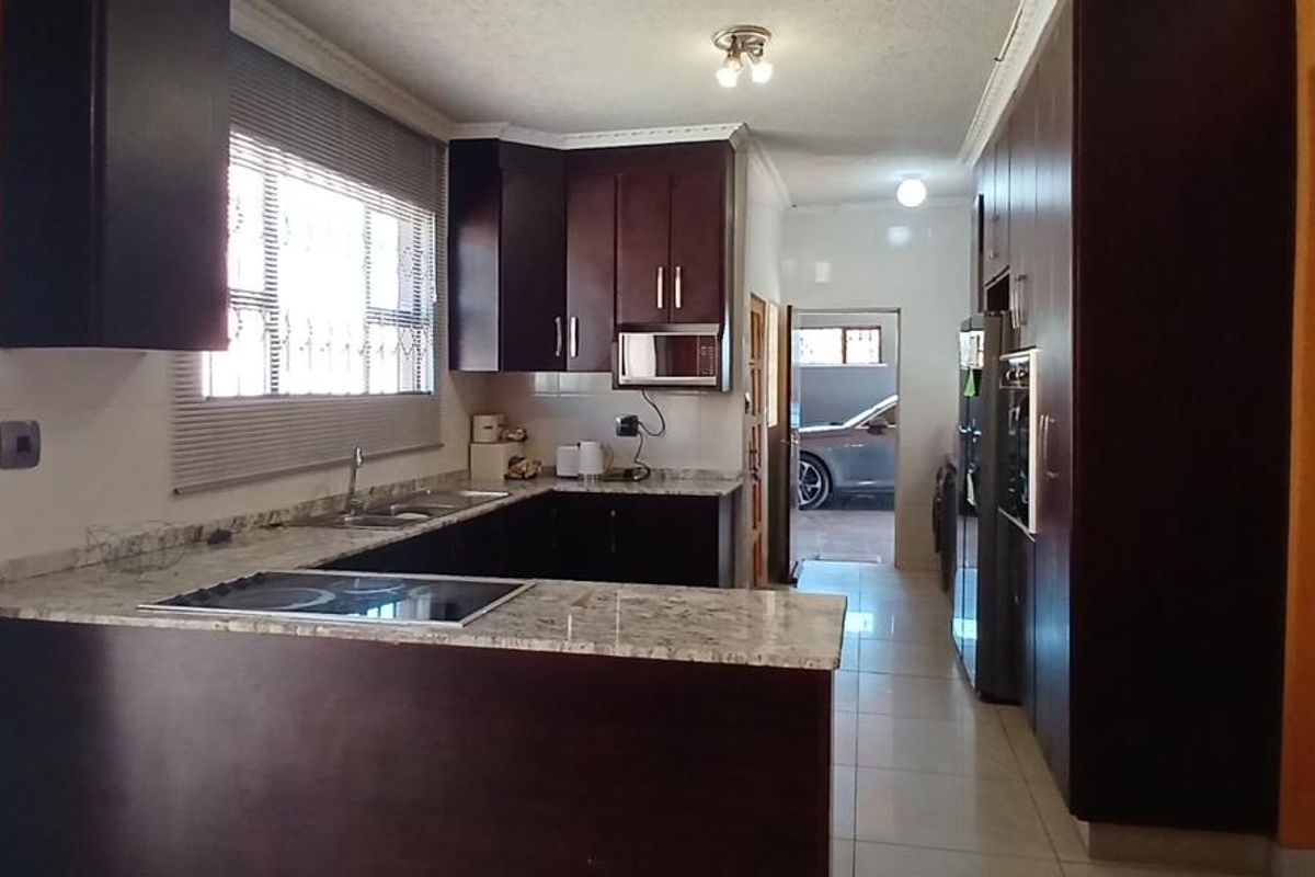 A functional kitchen featuring dark wood cabinetry, granite countertops, built-in appliances, and tiled flooring, offering a clean and practical workspace.