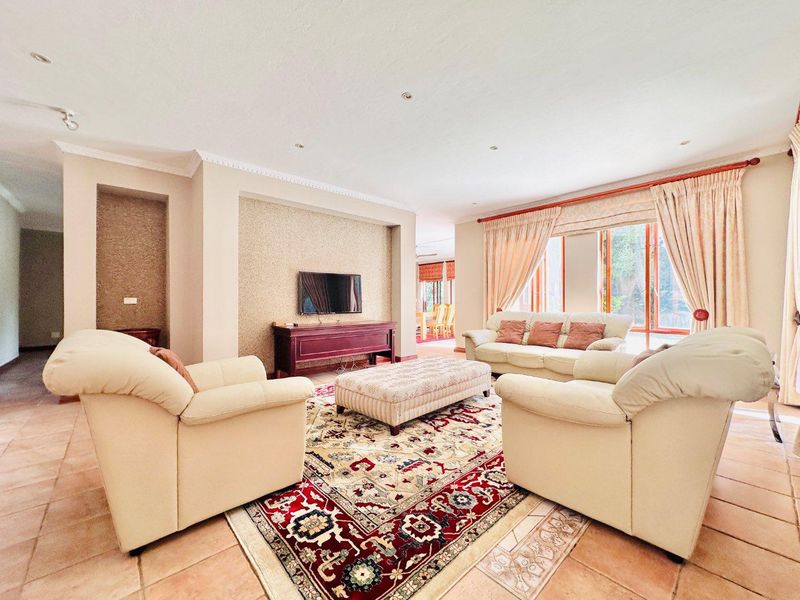 Spacious open-plan living area featuring tiled flooring, recessed wall alcoves, and large windows with natural light, seamlessly connecting to the dining space.