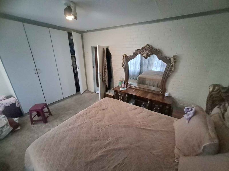 A bedroom featuring built-in cupboards and a painted brick feature wall, requiring cosmetic updates to improve the overall aesthetic and condition.