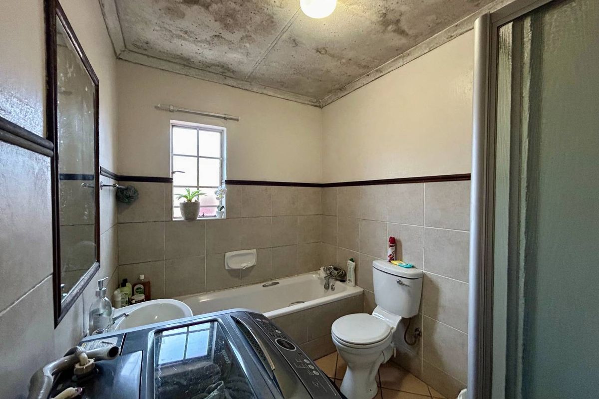 A functional bathroom featuring a bathtub, toilet, and shower enclosure, currently requiring significant ceiling repairs and cosmetic updates to improve the overall condition.