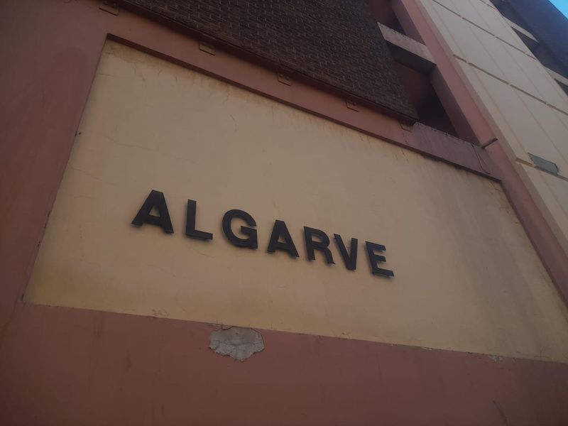 Exterior view of the apartment building facade featuring the property name signage and visible wear to the exterior paint finish.