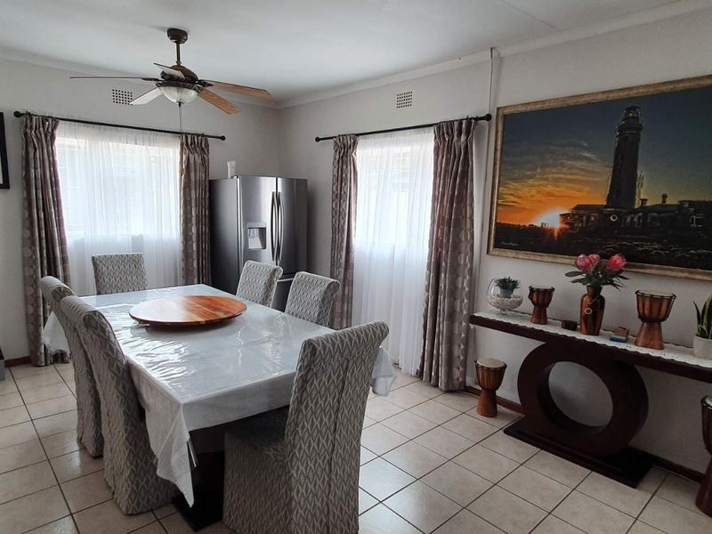 A dining room featuring tiled flooring, a ceiling fan, and dual windows with curtain treatments, providing a functional space for meals.