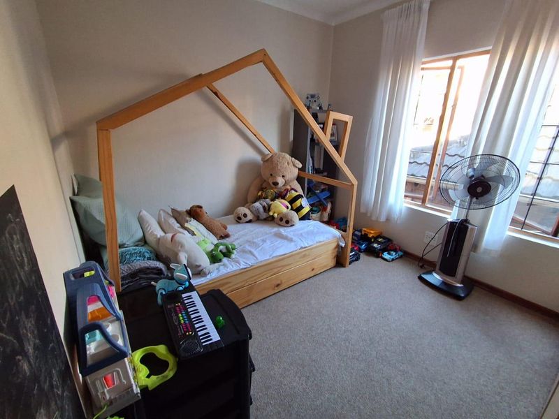 A bedroom featuring carpeted flooring and a window with natural light, currently utilized as a child's room.