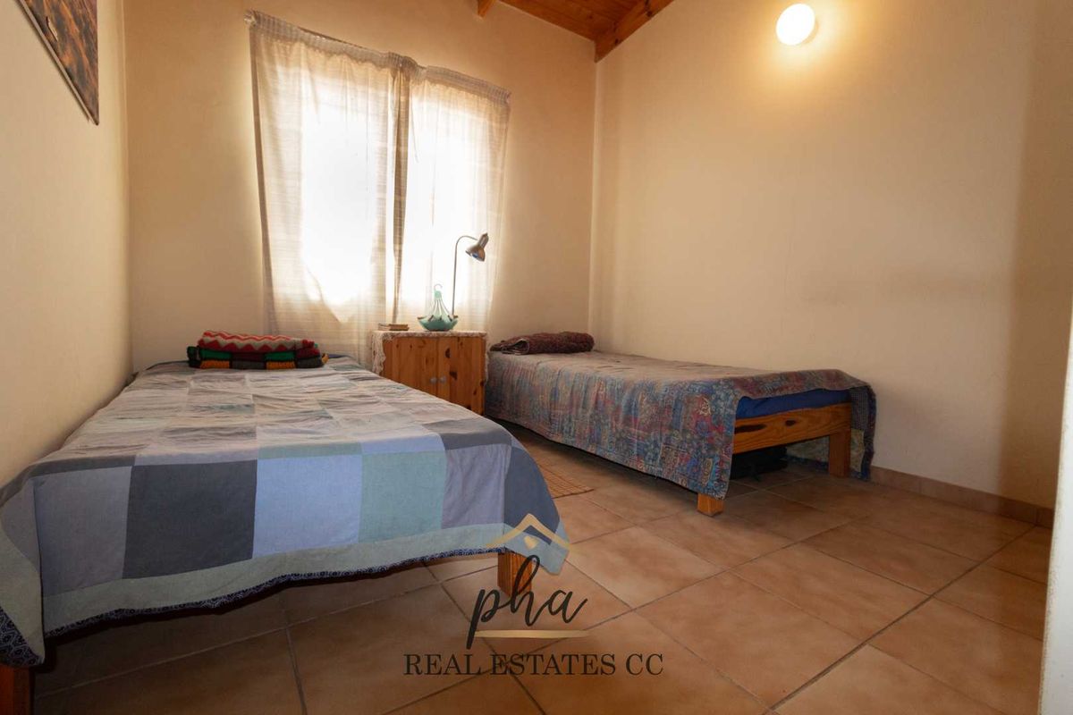 A bedroom featuring tiled flooring and a vaulted timber ceiling, providing a functional space with natural light.