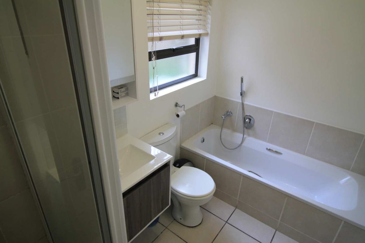 A clean, functional bathroom featuring a bathtub, separate shower enclosure, vanity cabinet, and neutral floor-to-wall tiling.
