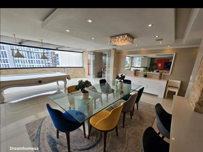 Spacious open-plan living and dining area featuring modern recessed ceiling lighting, large windows, and polished tiled flooring in a contemporary penthouse setting.