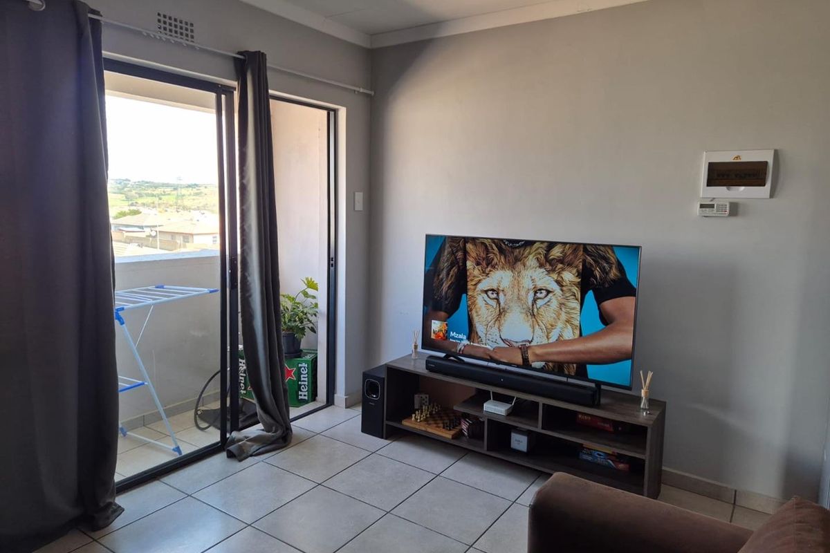 Living room featuring tiled flooring and sliding glass doors leading to a private balcony with exterior views.