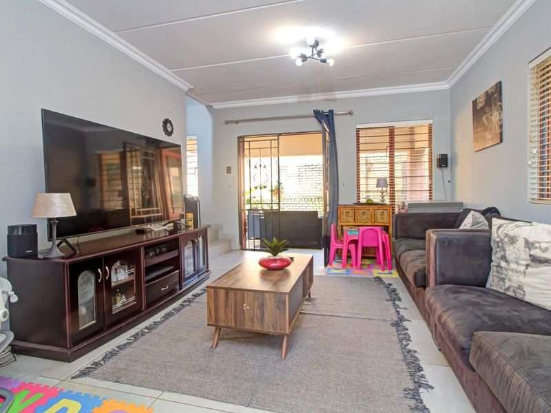 A comfortable living room featuring tiled flooring, ceiling cornices, and a sliding door providing access to the outdoor patio area.