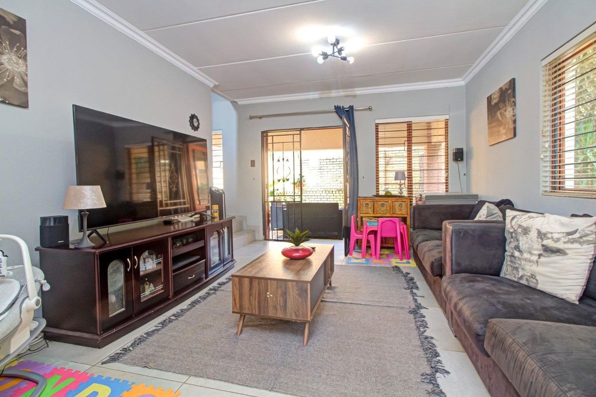 A comfortable living room featuring tiled flooring, ceiling cornices, and a sliding door providing access to the outdoor patio area.