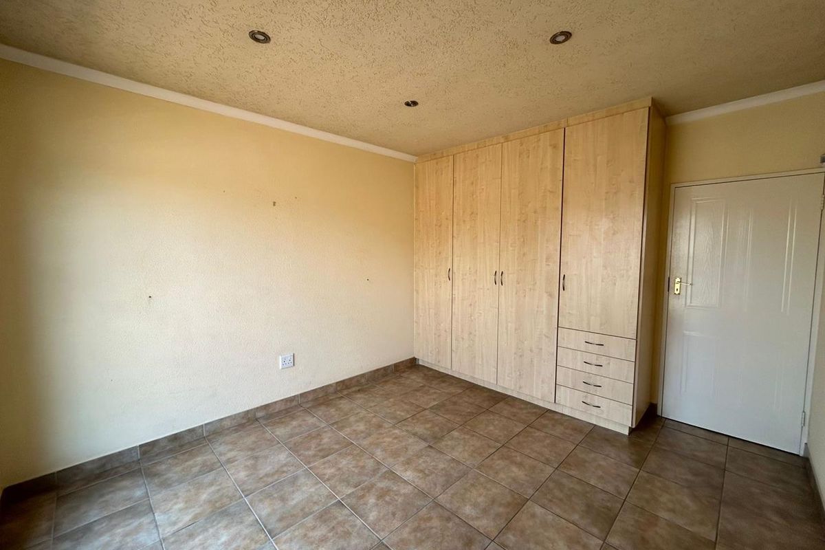 A vacant bedroom featuring tiled flooring, recessed downlighting, and ample built-in cupboard storage space.
