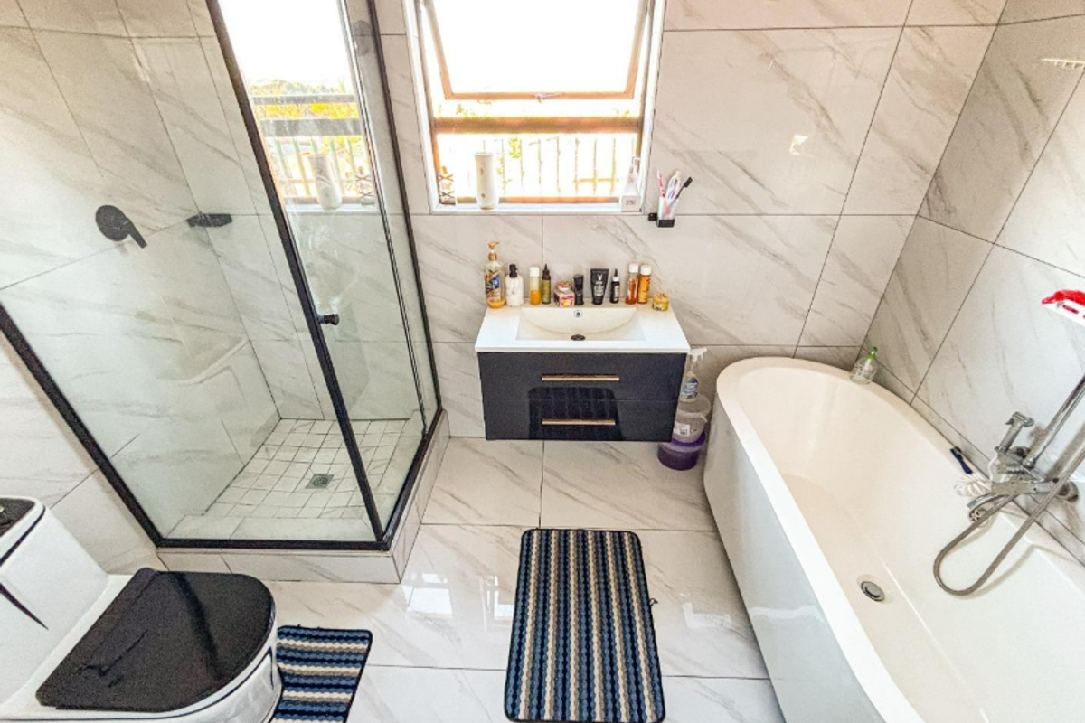 Modern bathroom featuring a glass-enclosed shower, a sleek wall-mounted vanity, a freestanding bathtub, and contemporary marble-look tiling throughout.