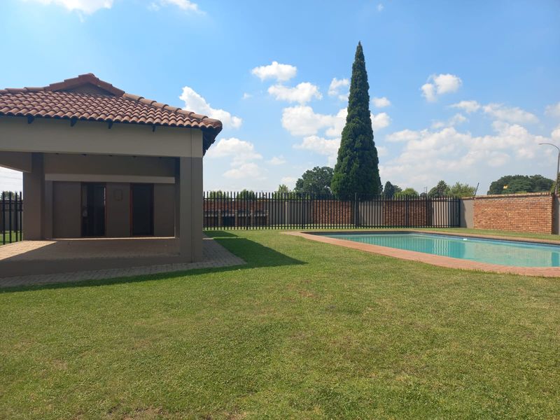 Spacious backyard featuring a well-maintained swimming pool, a covered patio area, and secure perimeter fencing with established lawn.