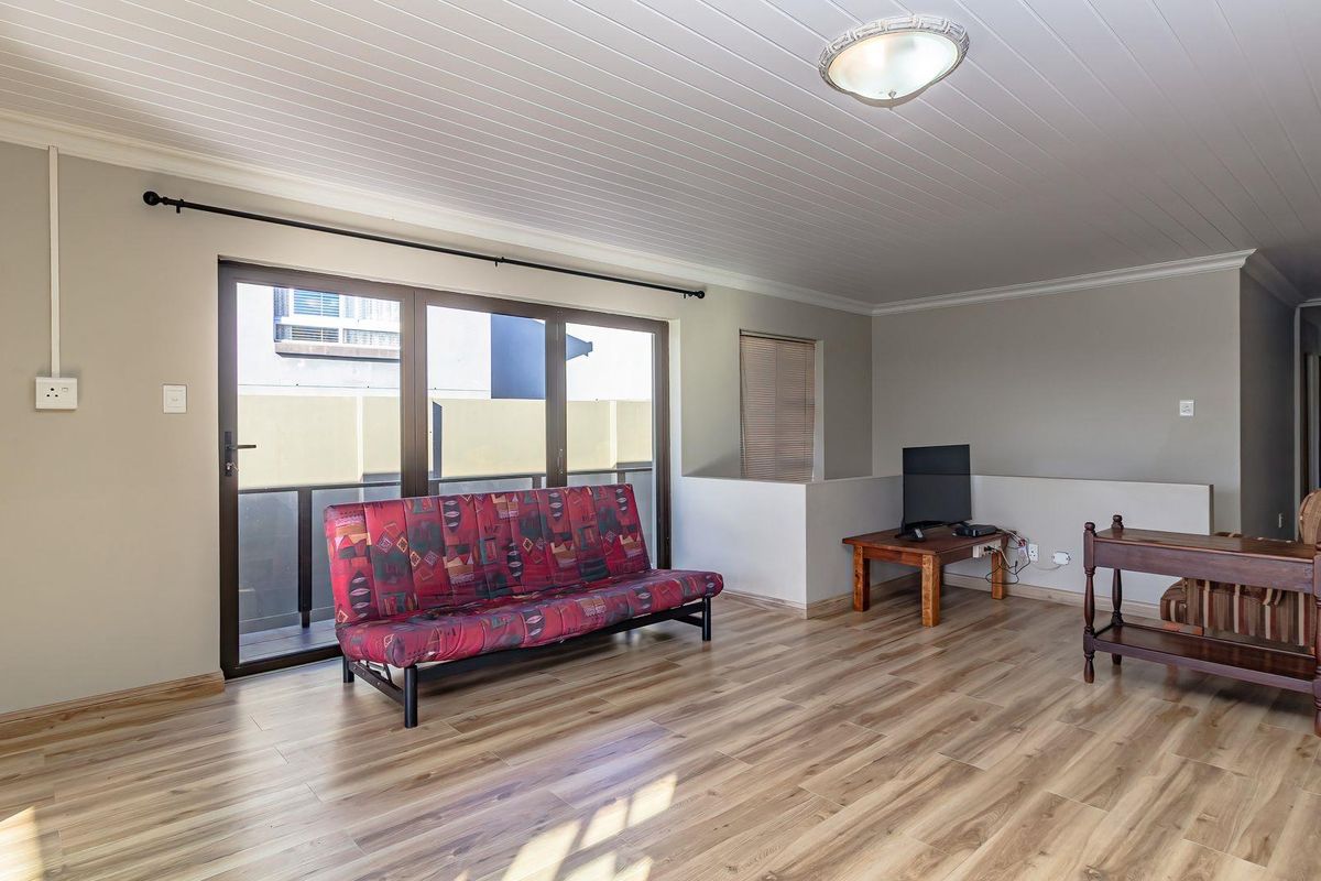 A spacious living area featuring laminate flooring, a tongue and groove ceiling, and a large sliding glass door providing access to an outdoor space.