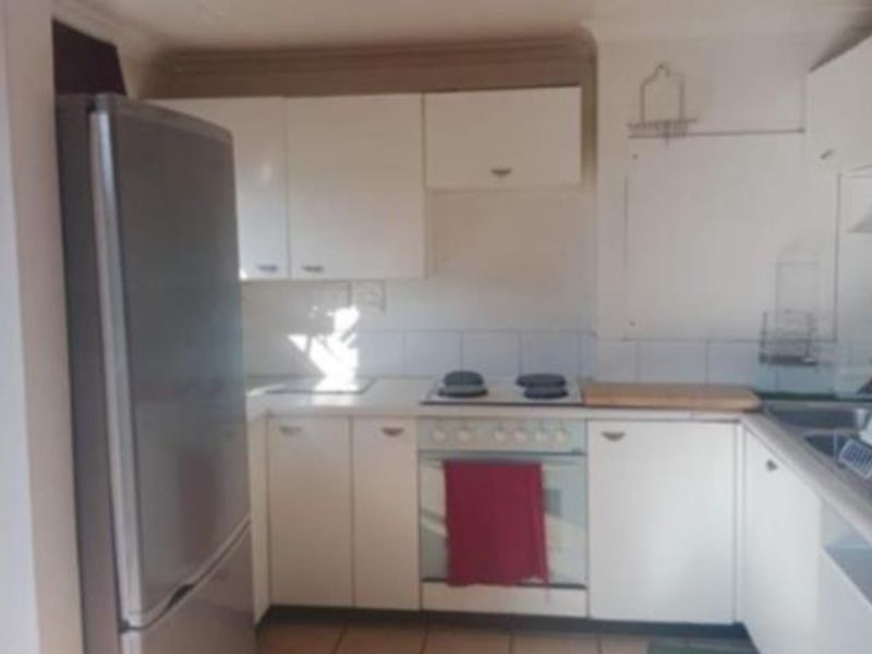A functional kitchen featuring white cabinetry, a tiled backsplash, and integrated cooking appliances, offering a clean and practical layout for daily use.