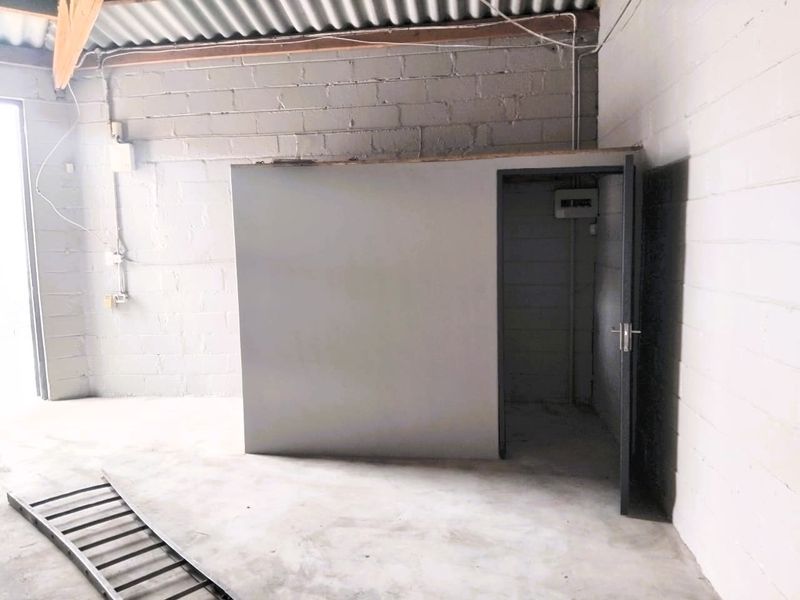 Industrial utility space featuring exposed brick walls, concrete flooring, and a dedicated enclosed area housing the electrical distribution board.