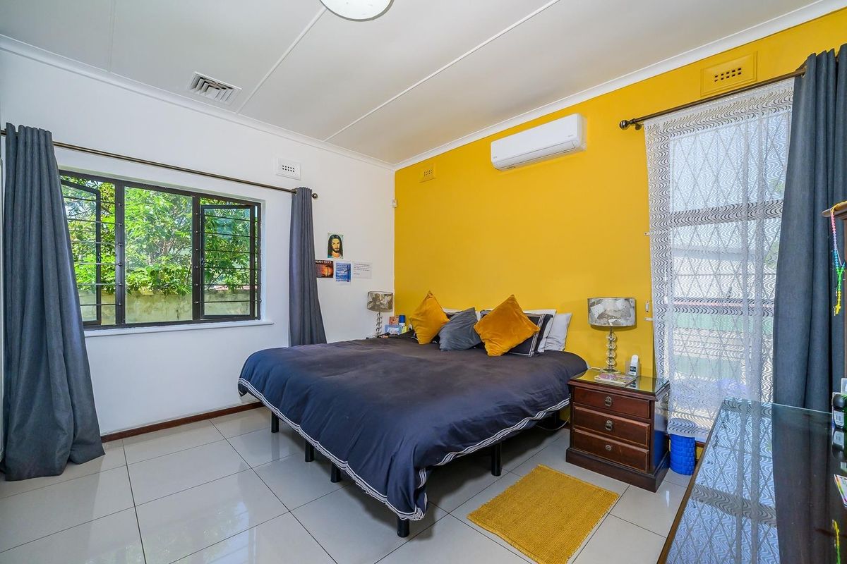 A bedroom featuring tiled flooring, a split-system air conditioner, and large windows allowing natural light.