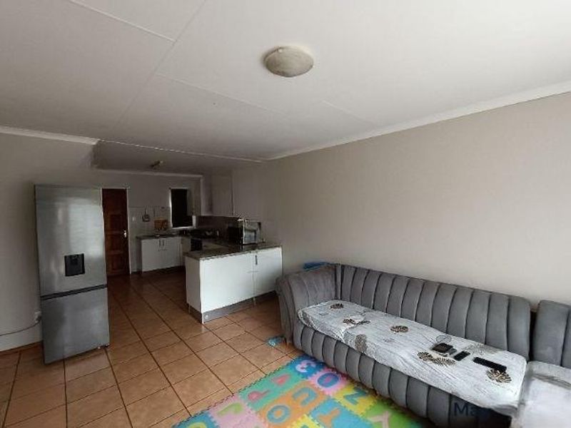 Open plan living area featuring tiled flooring and a functional kitchen space with built-in cabinetry and countertops.