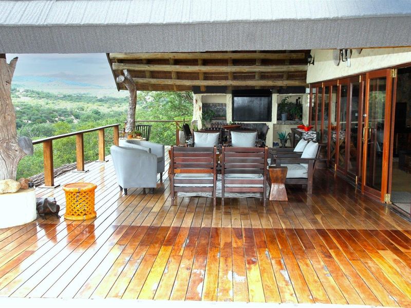 Spacious covered timber deck featuring a built-in fireplace, timber folding doors, and expansive views of the surrounding landscape.