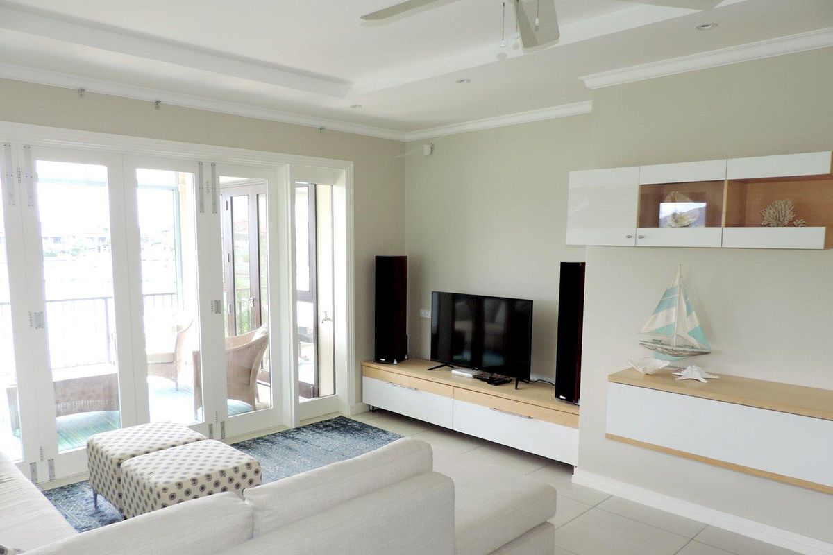 Bright living room featuring tiled flooring, recessed ceiling detail, and large glass sliding doors providing seamless access to the balcony.