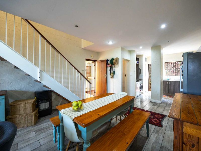 Open-plan living and dining area featuring a staircase, tiled flooring, and integrated kitchen access, offering a functional layout for modern townhouse living.