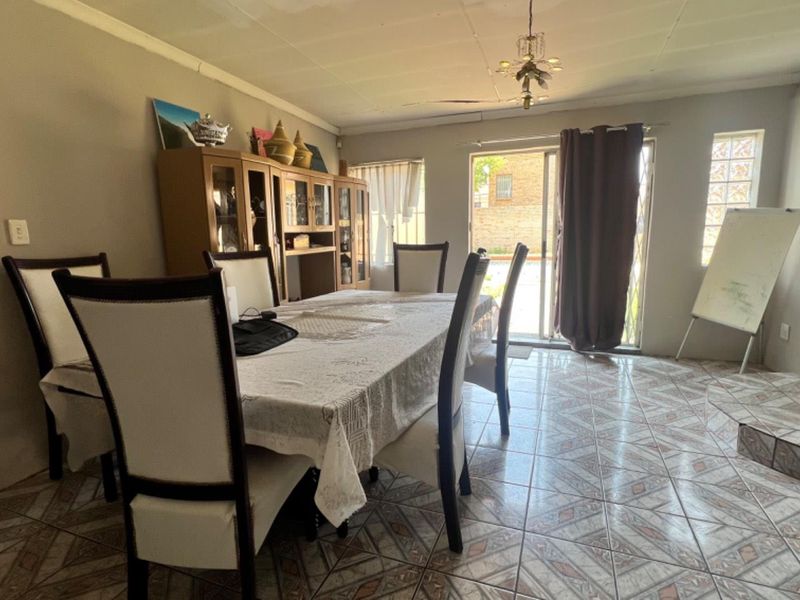A dining room featuring tiled flooring, a sliding glass door providing outdoor access, and a glass block window feature.