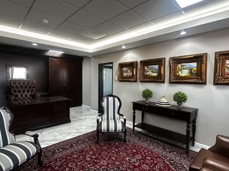 A professional office space featuring dark wood built-in cabinetry, polished marble flooring, and sophisticated recessed and cove lighting.