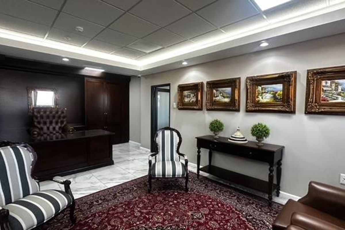 A professional office space featuring dark wood built-in cabinetry, polished marble flooring, and sophisticated recessed and cove lighting.